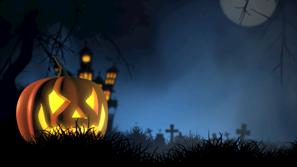 A glowing pumpkin in the foreground with a creepy, crooked manor with its lights on inside and a graveyard outside in the background.
